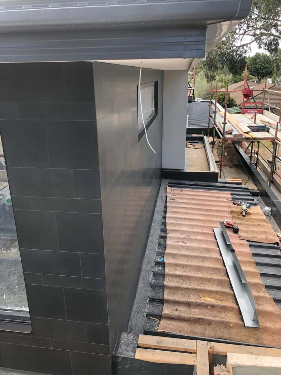 Dark charcoal large-format cladding wrapped around an exterior corner on a residential build.