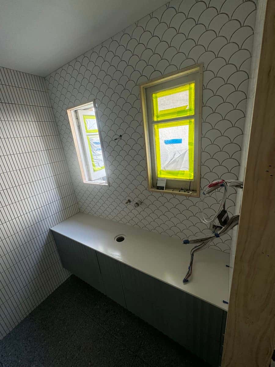 Vanity wall finished with white scallop-pattern feature tiles around two windows.