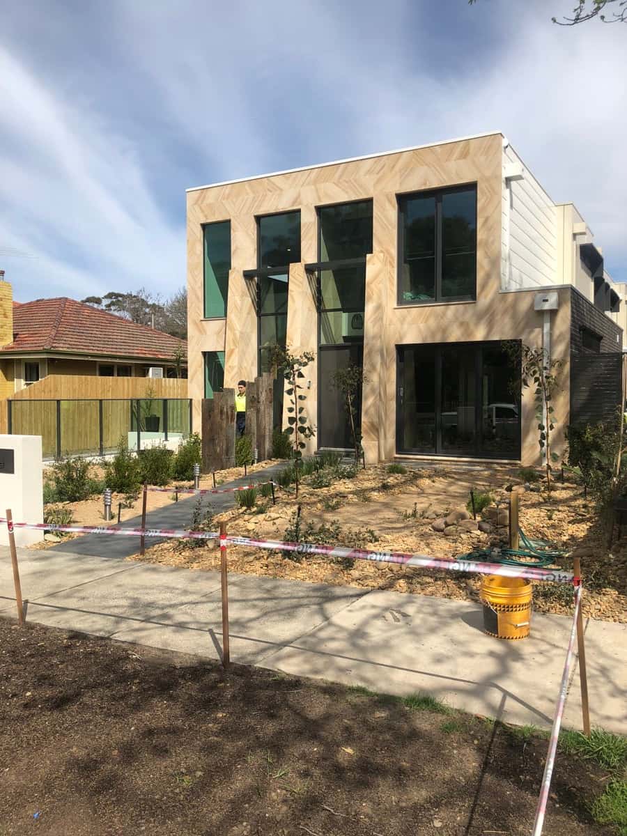 Modern double-storey home with a light herringbone tiled facade and black framed windows.